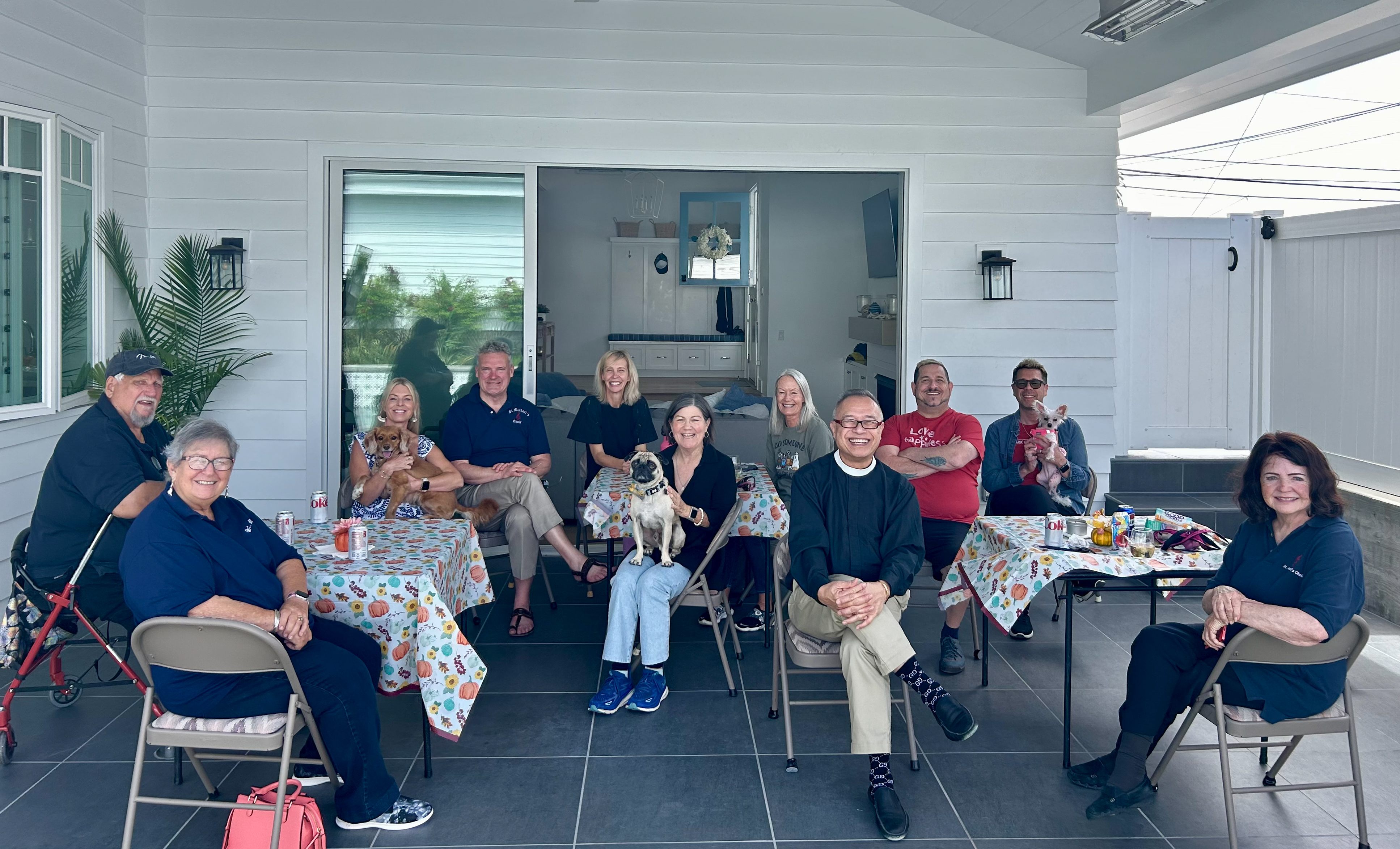 A group of parishioners sit smiling at tables on an outdoor patio.