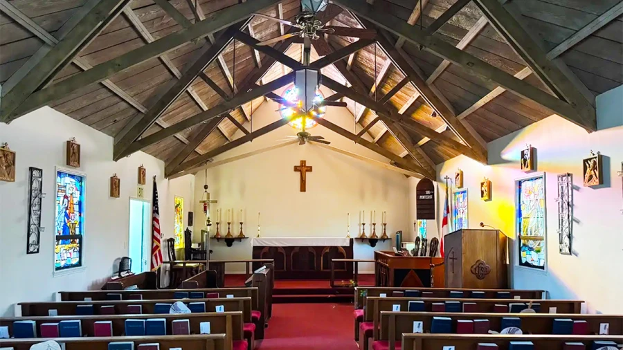 A view of the St. Michael's sanctuary, which features red carpet and arched wooden rafters.