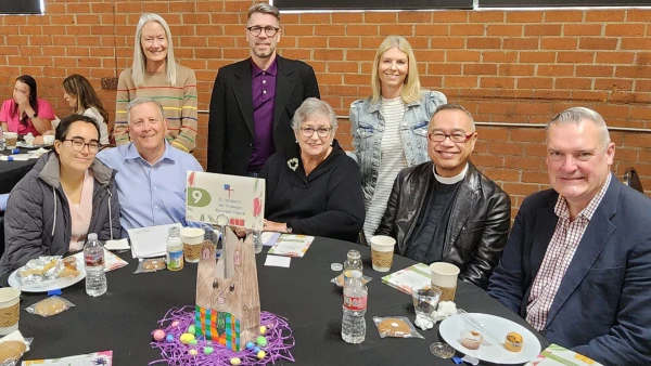 A group of church-goers pose at a table after sharing coffee hour refreshments.