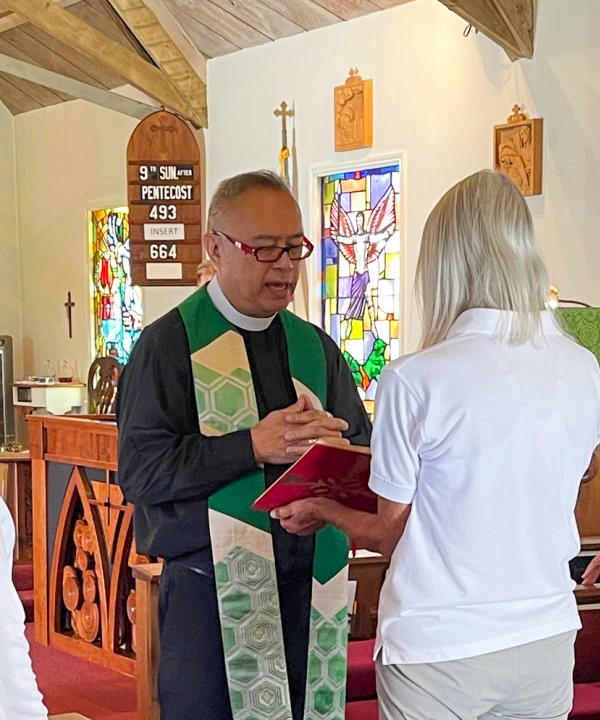 A parishioner holds the gospel and Fr. Joshua reads from it during a service.