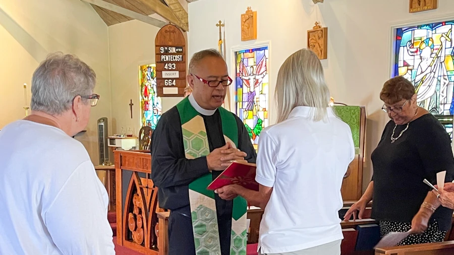 A parishioner holds the gospel and Fr. Joshua reads from it during a service.