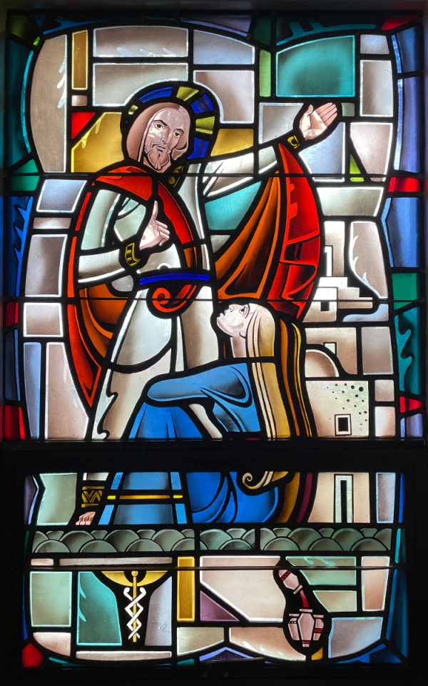 Stained glass window: A man in robes speaks while a woman at his feet listens.