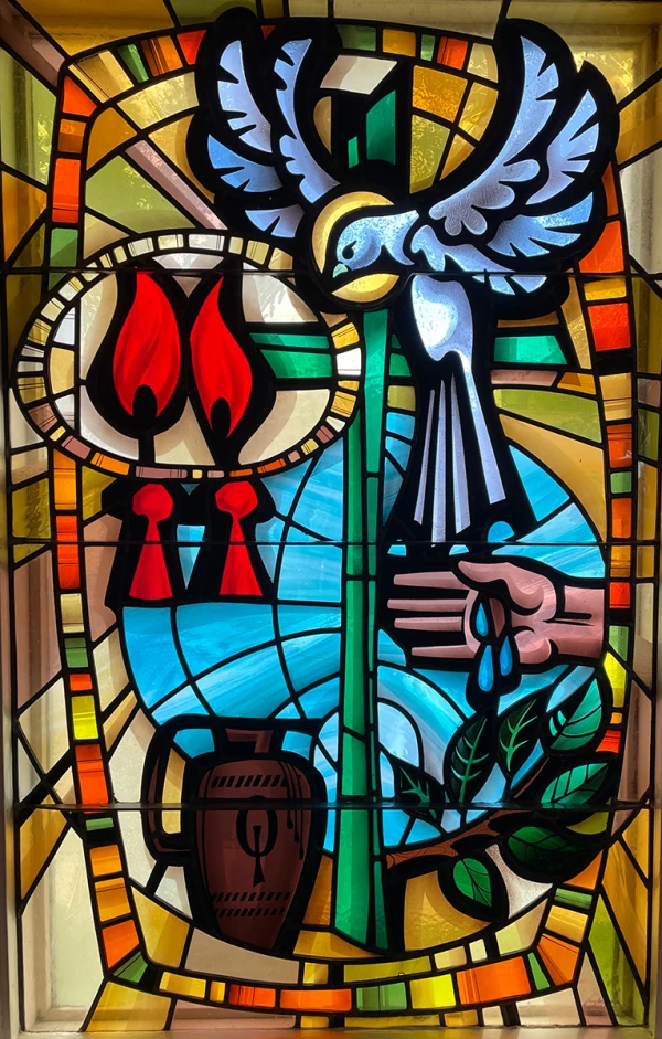 Stained glass window showing a dove, flames, a budding tree and water.
