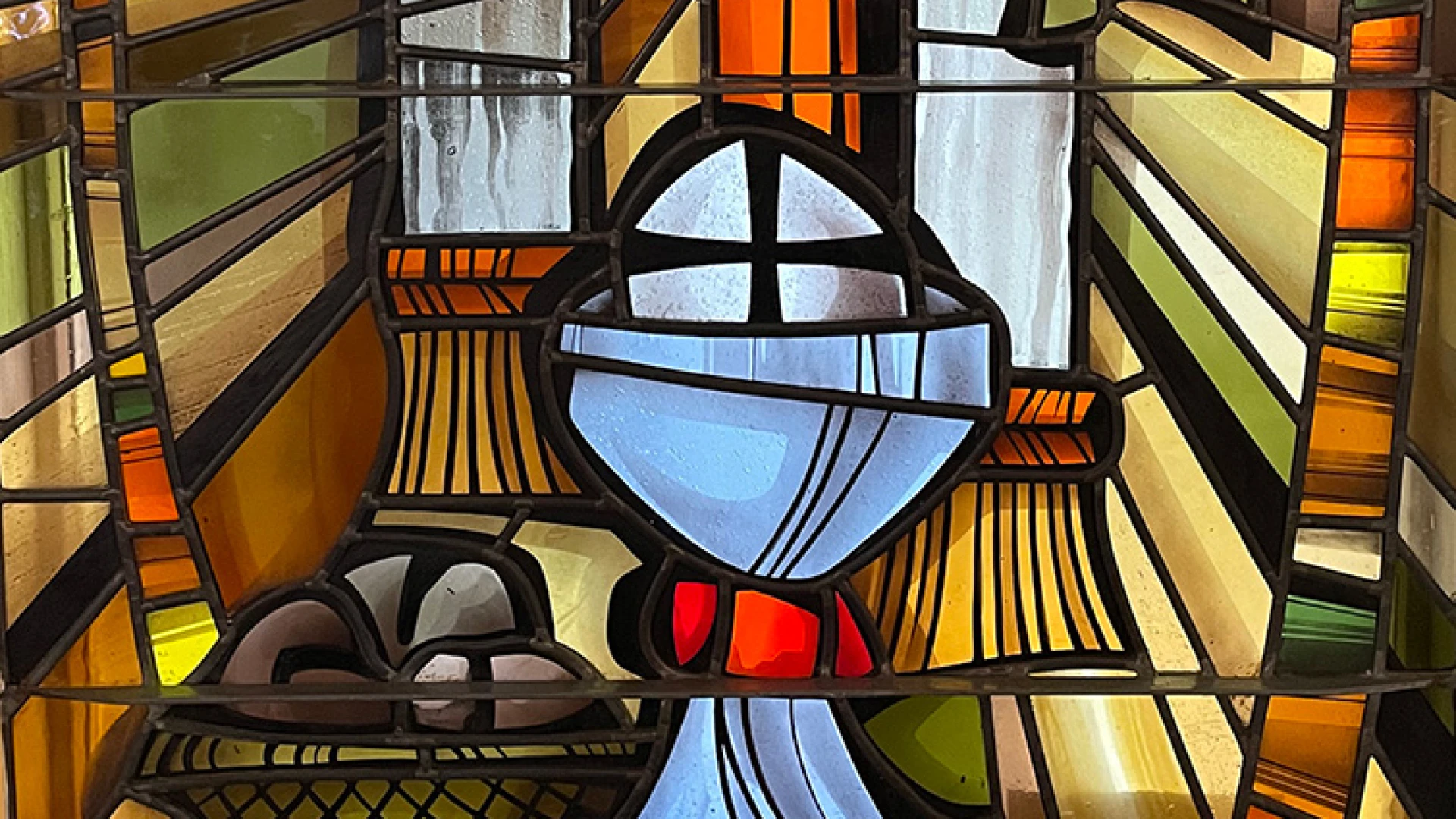 Stained glass window: elements of the Eucharist, bread, wine, and other symbols of Christian worship.