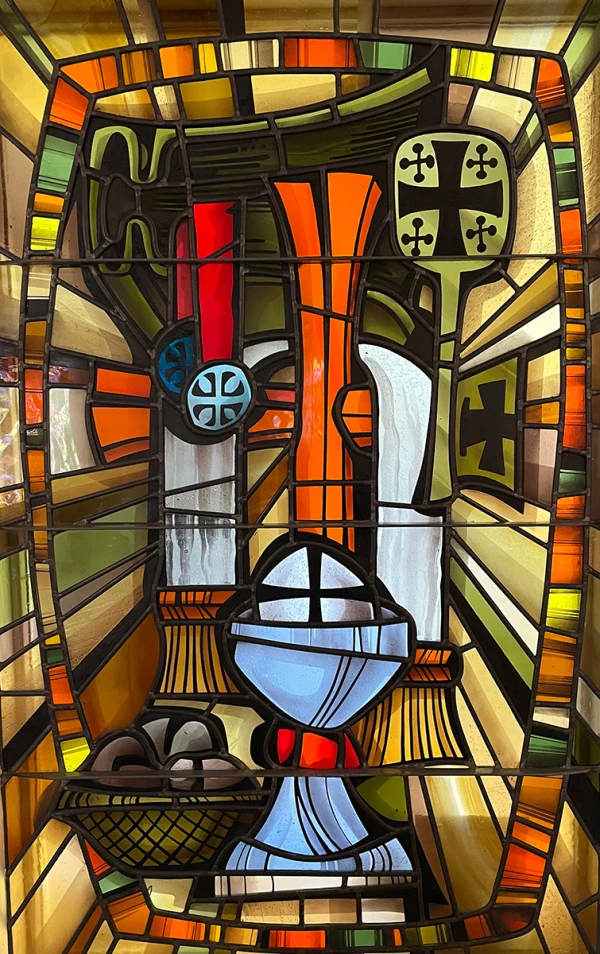 Stained glass window: elements of the Eucharist, bread, wine, and other symbols of Christian worship.