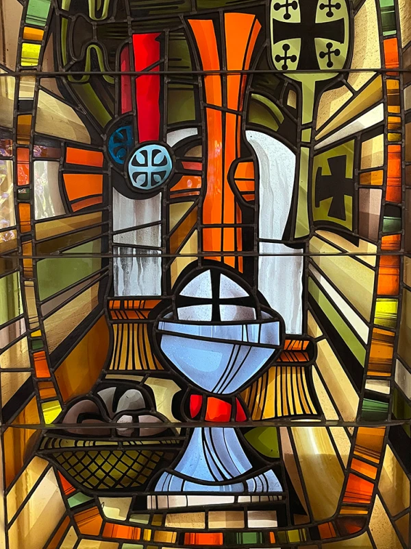 Stained glass window: elements of the Eucharist, bread, wine, and other symbols of Christian worship.