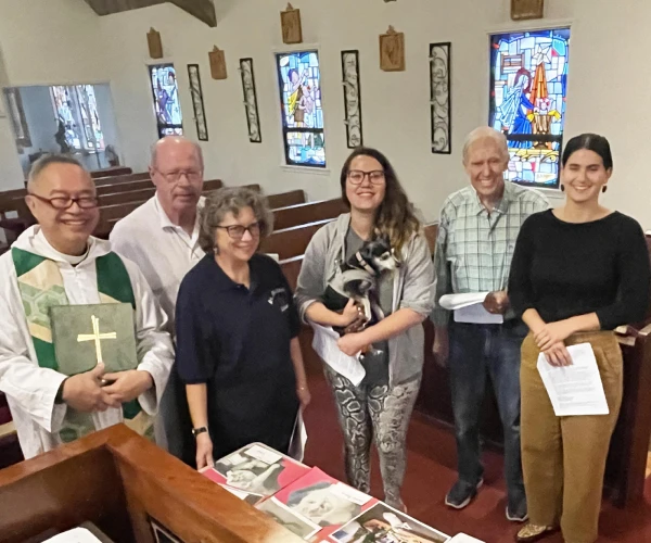 A group of parishioners and Fr. Joshua pose in the sanctuary after a service.